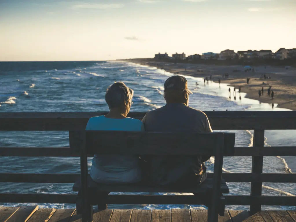 couple sitting on a bench facing the sea
