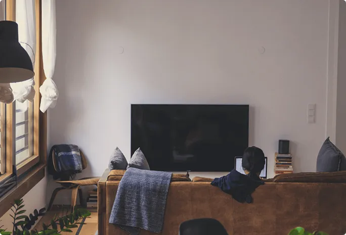 A young woman is sitting on her sofa in front of the television.