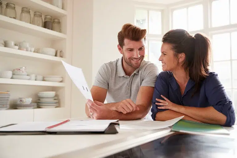 Un couple assis à une table regardant des documents aide financière déménagement