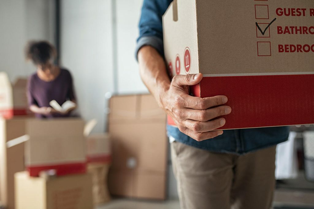 Homme portant un carton de déménagement