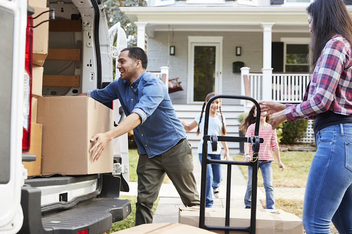 Une famille qui décharge un camion de déménagement devant leur nouvelle maison