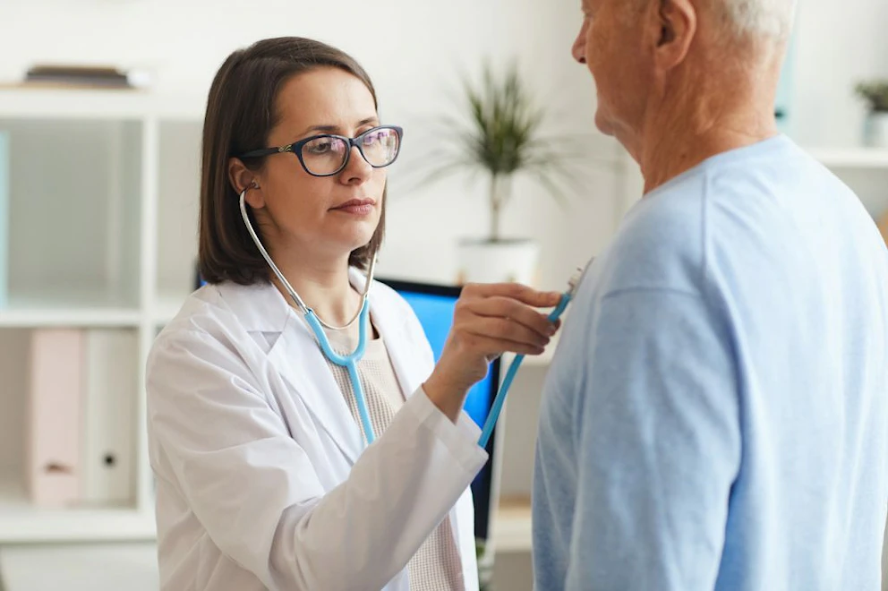 Une femme médecin ausculte un homme âgé à l'aide d'un stéthoscope