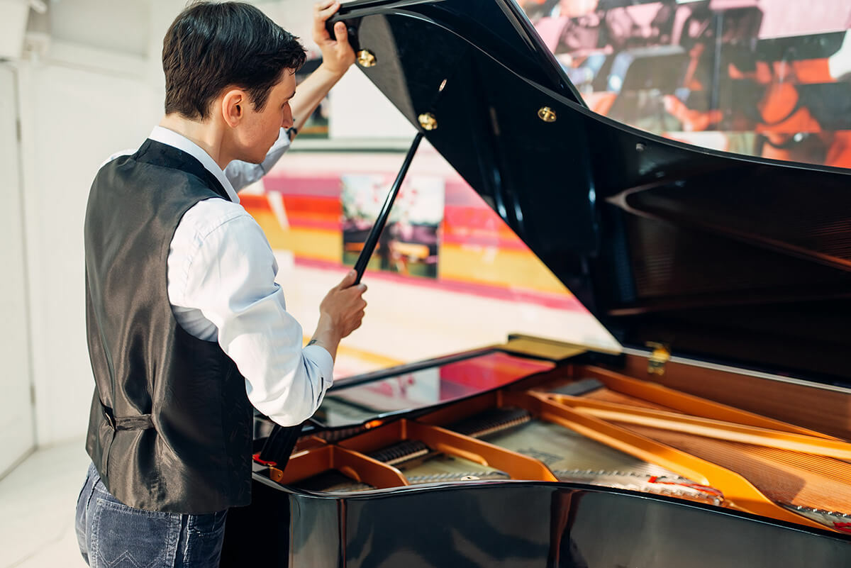 Un jeune homme ouvrant un piano à queue noir