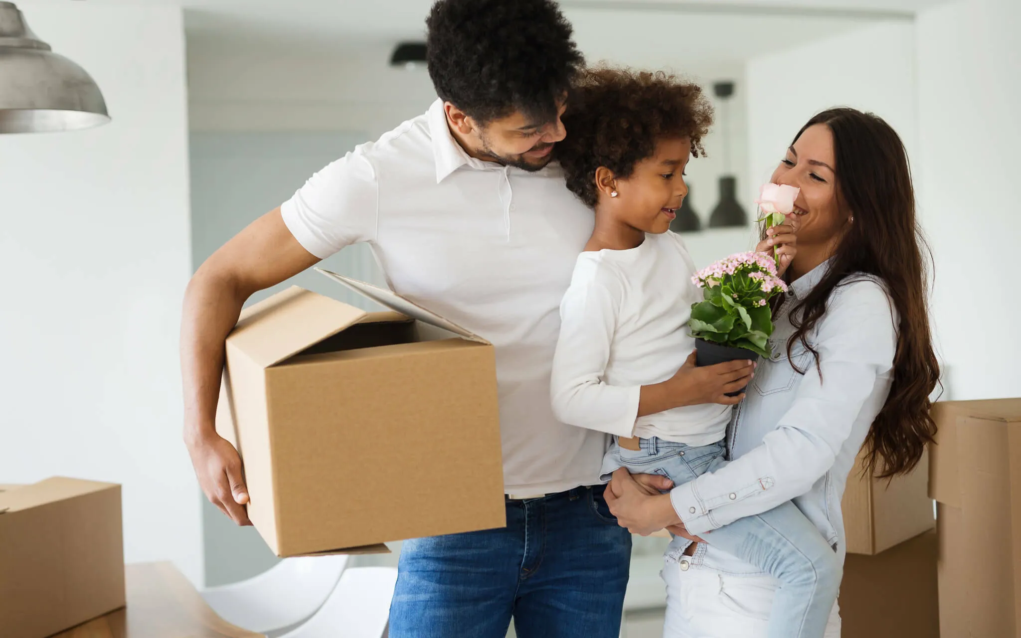 Une famille heureuse portant un carton de déménagement et une petite plante
