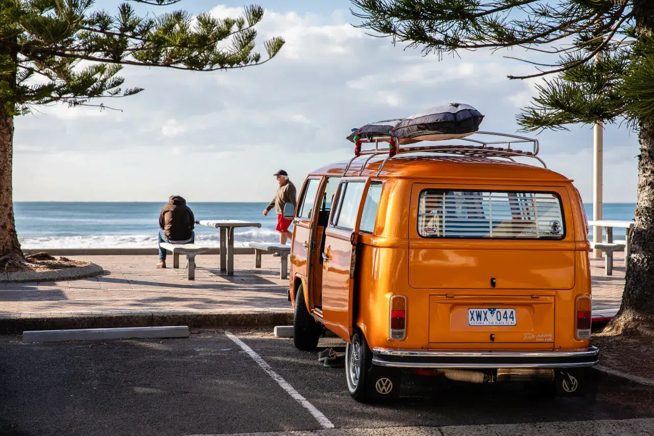Combi Volkswagen orange garé près de la plage