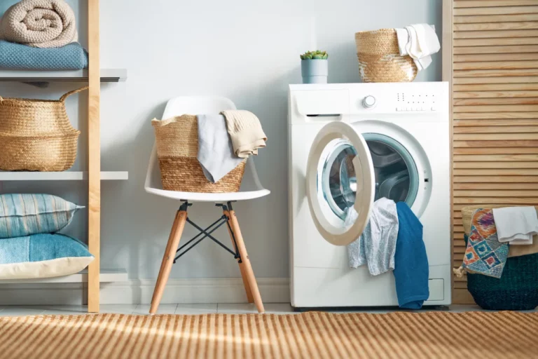 Une machine à laver le linge au hublot ouvert et des vêtements qui en débordent