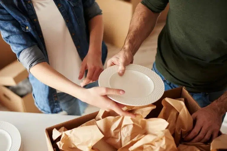Un couple emballe une assiette avant de la mettre en carton de déménagement