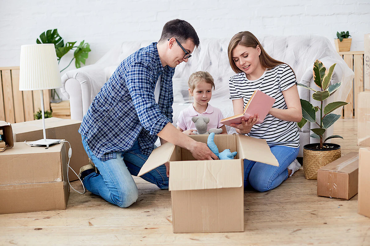 Un couple et leur petite fille mettent en carton leurs affaires pour déménager