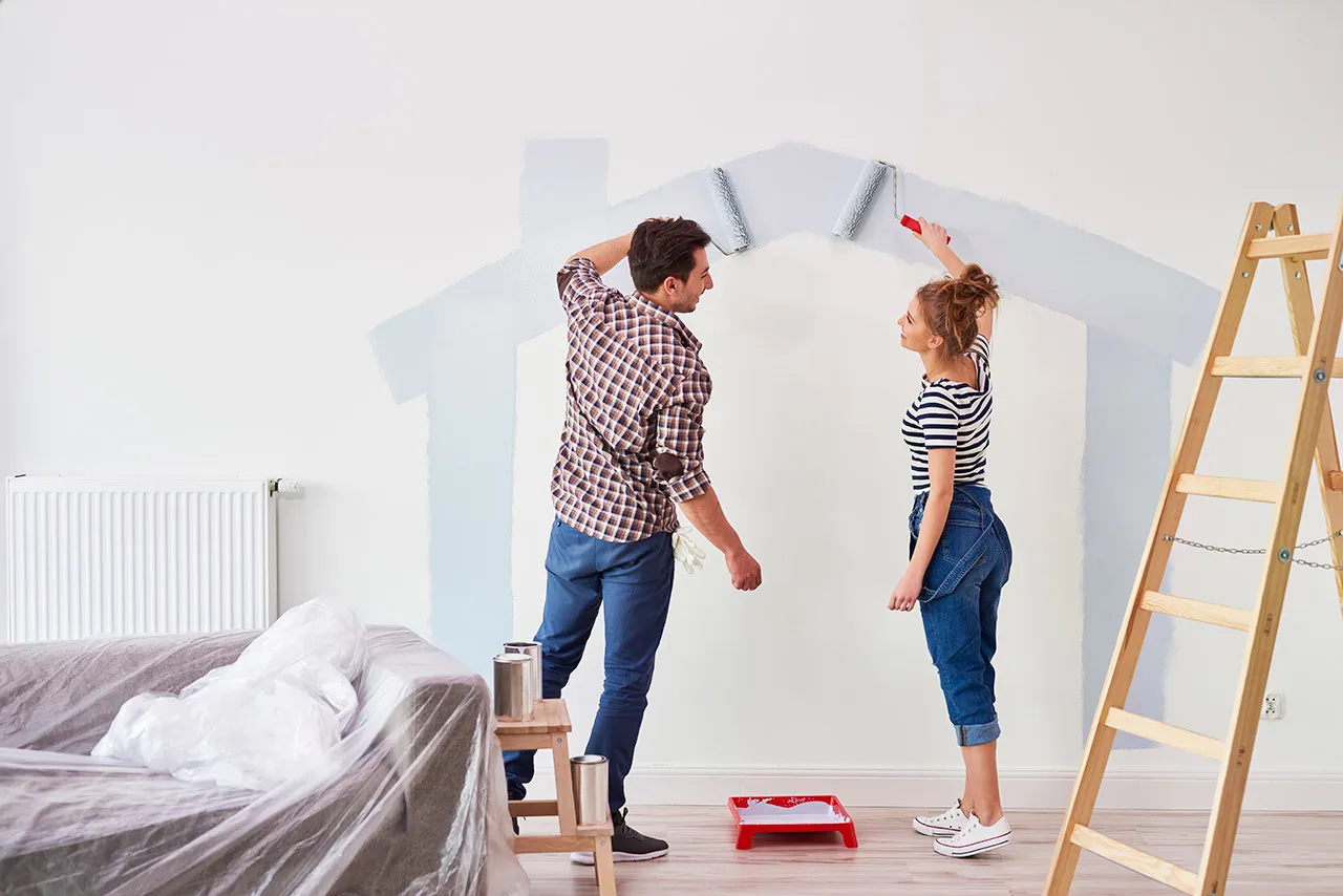 Couple qui peint la forme d'une maison sur un mur de leur salon