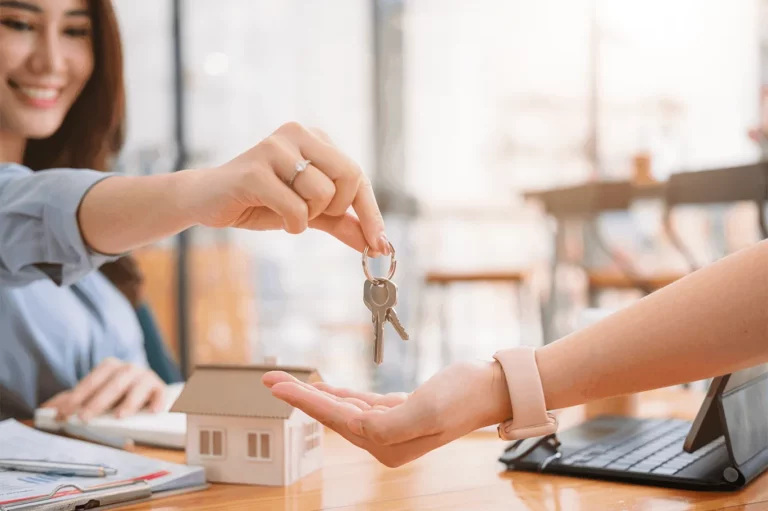 Un jeune femme tend les clés d'une maison à une personne