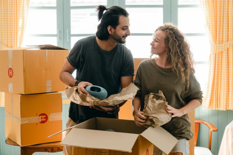 Un homme et une femme se regardent amoureusement pendant qu'ils emballent des vases et les mettent en carton de déménagement