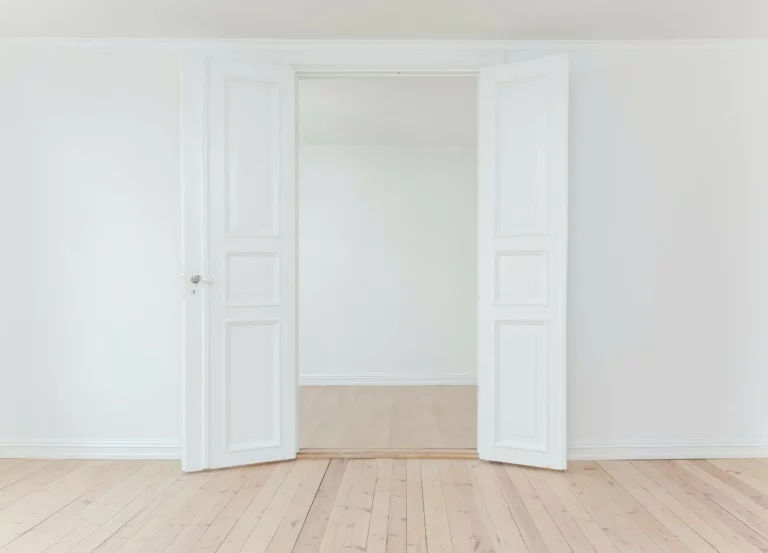 Pièce vide blanche donnant sur des portes ouvertes