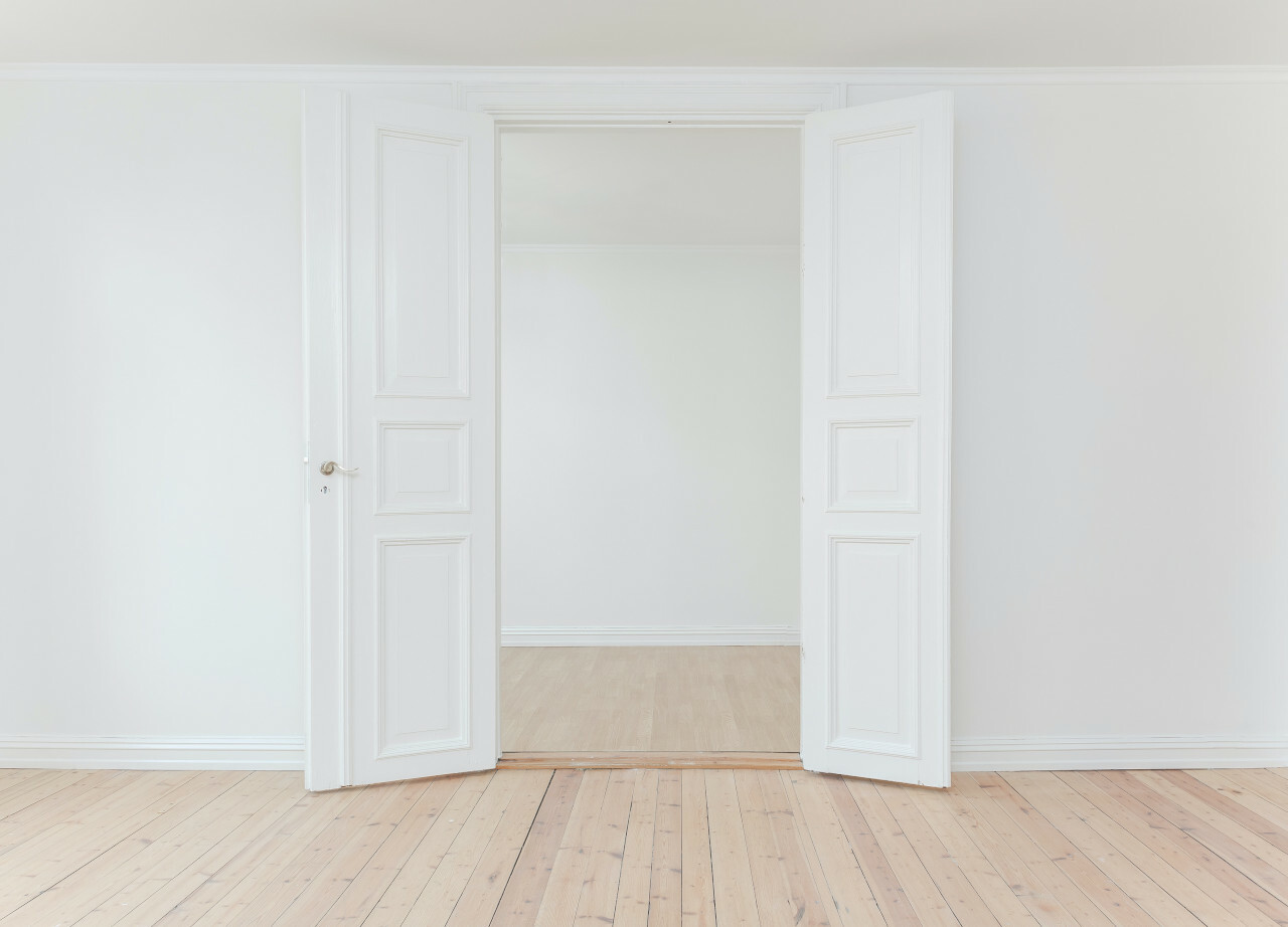Pièce vide blanche donnant sur des portes ouvertes