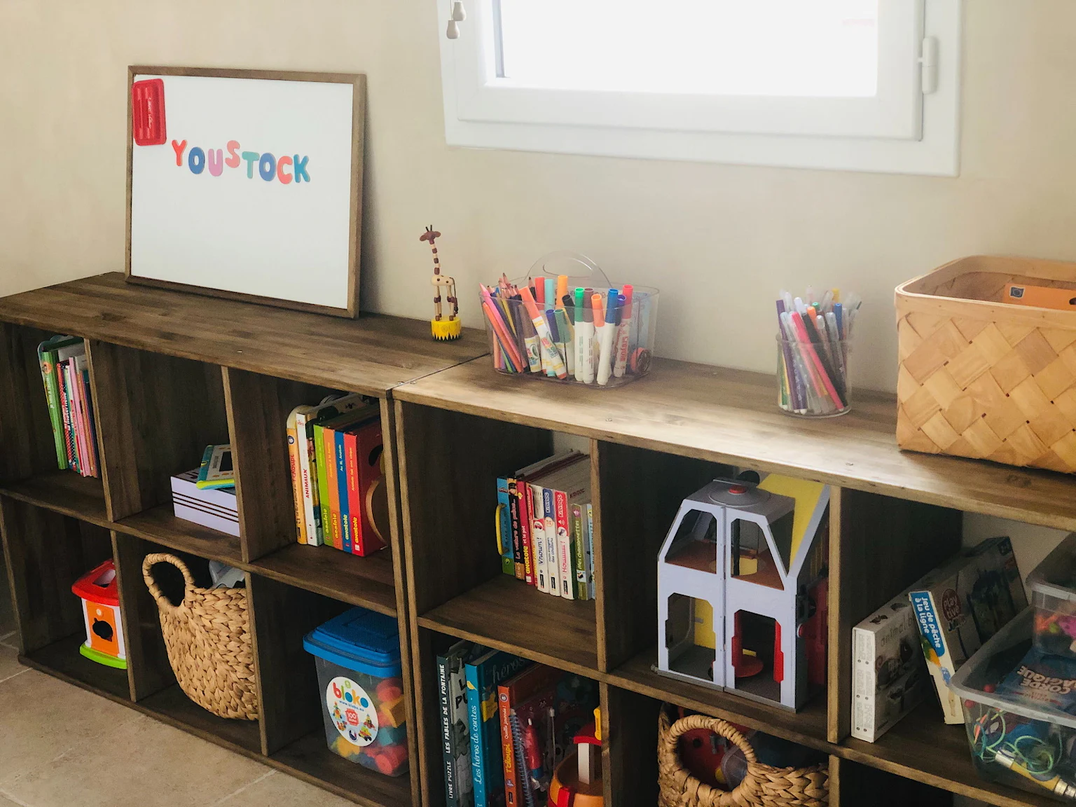 Un meuble à casiers en bois foncé dans lequel sont rangés des jouets et des livres pour enfant