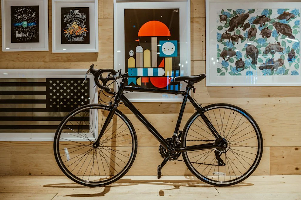 Un vélo adossé à un mur rempli de cadres photos