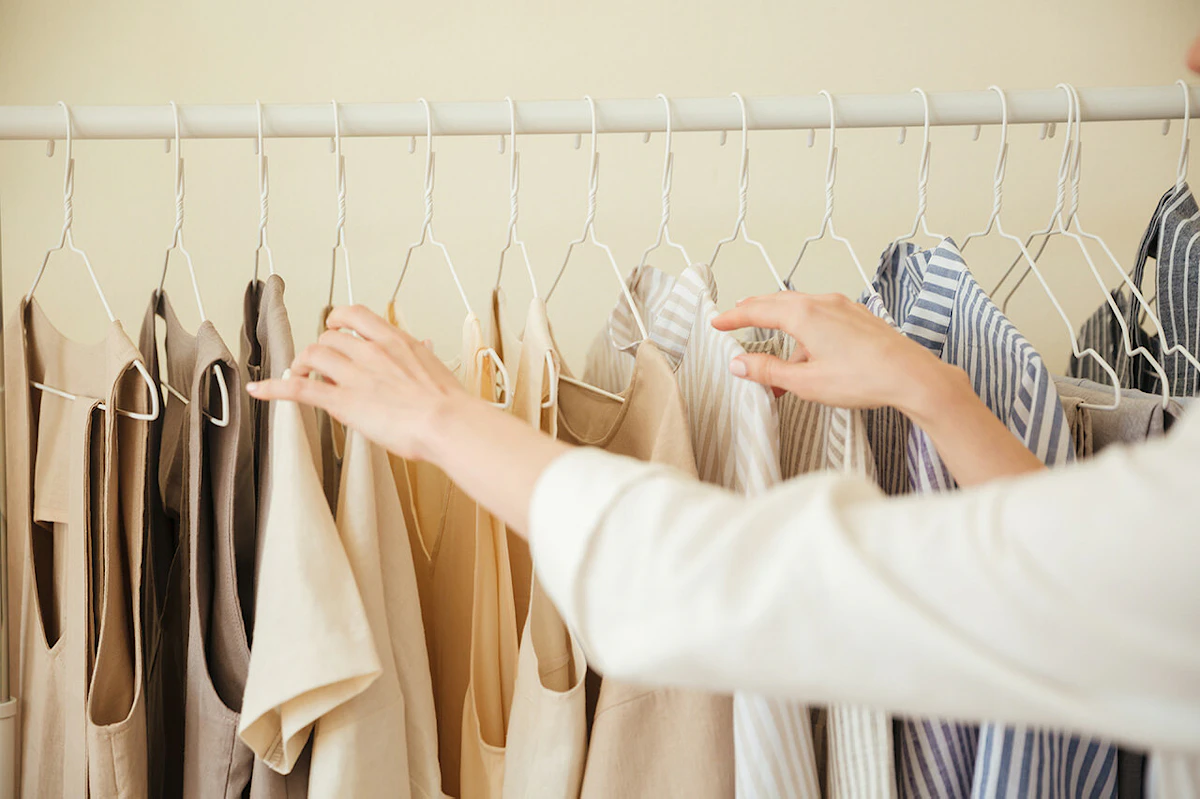 2 mains de femmes remplaçant des vêtements sur un portant