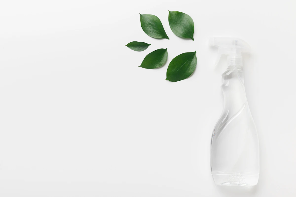Pulvérisateur transparent avec des feuilles sur fond blanc