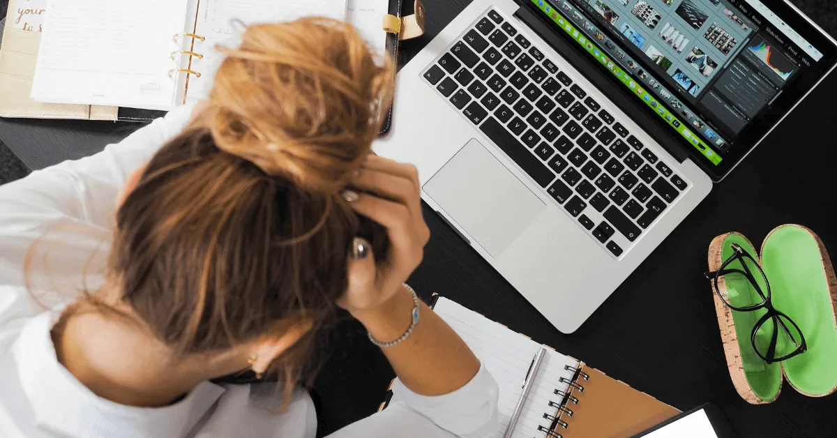 A young woman holds her head in front of her computer screen.