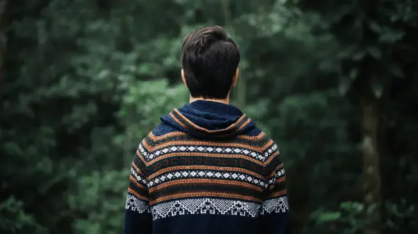 A man is standing with his back to us in a forest