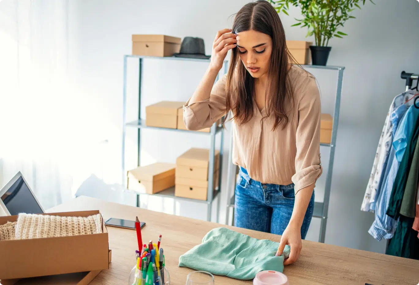 A woman folds a shirt on a table.