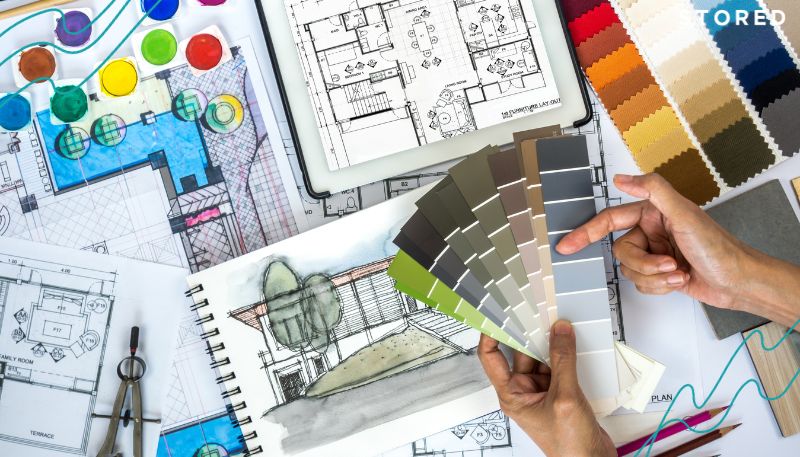 An image of a person holding color cards with design schemes for a garage in the background for their garage conversion