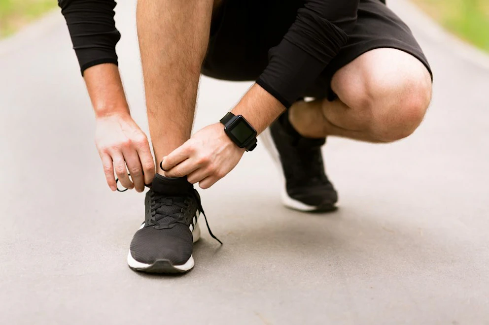 Un jeune homme en tenue de sport faisant ses lacets de chaussure