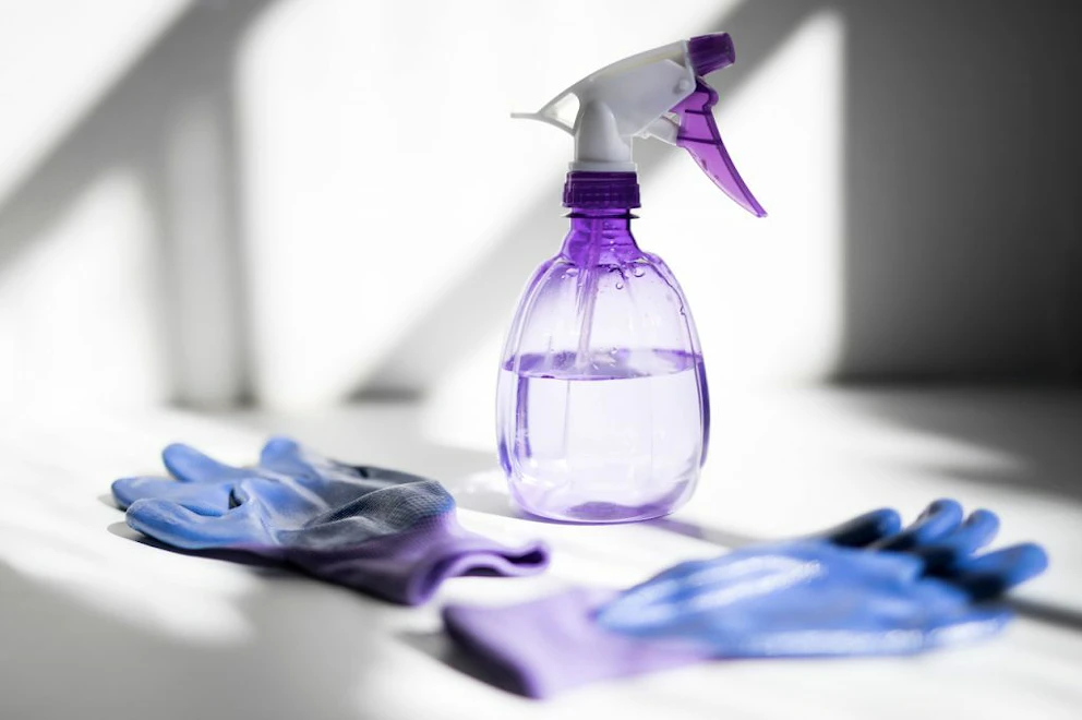 Pulvérisateur rempli et posé à côté de gants de nettoyage