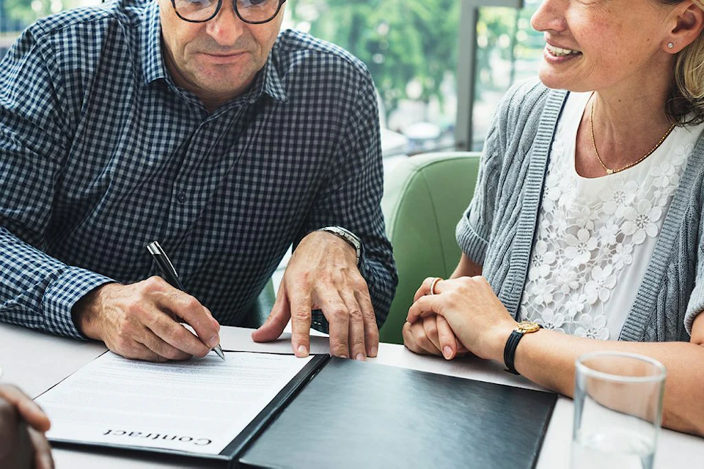 Un couple de personnes âgées signe un contrat de déménagement