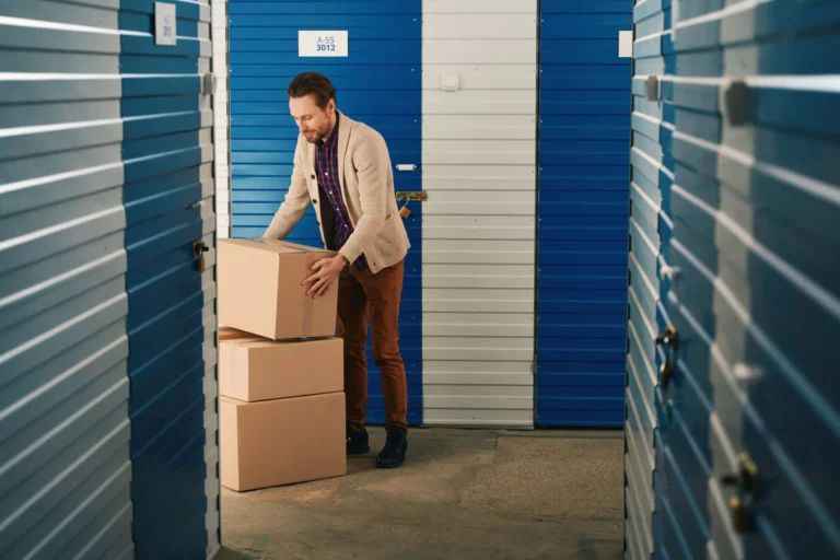 Guy with big cardboard boxes into warehouse with self-storage unit