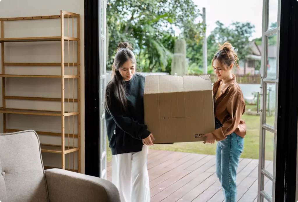Deux jeunes femmes portent un carton