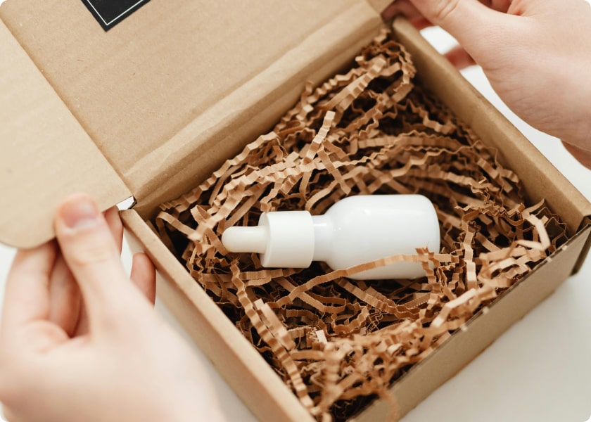 Petit flacon blanc de sérum dans un carton rempli de frisures de calage