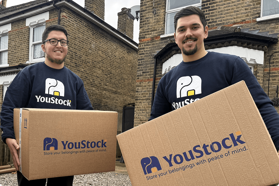 Two YouStock movers each carry a YouStock branded cardboard box - Store your belongings with peace of mind.