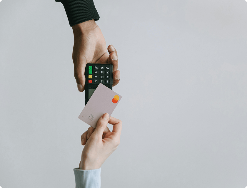Zoom in on a hand paying with a MasterCard on an EFTPOS terminal held by another hand.