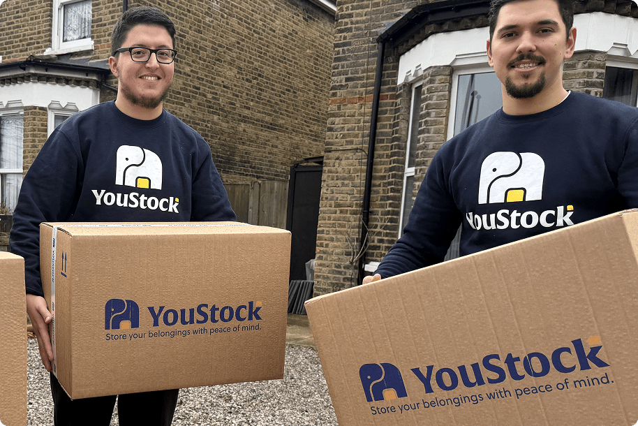 Two YouStock movers each carry a YouStock branded cardboard box - Store your belongings with peace of mind.