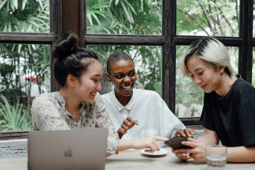 Trois amies assises à une table qui rigolent