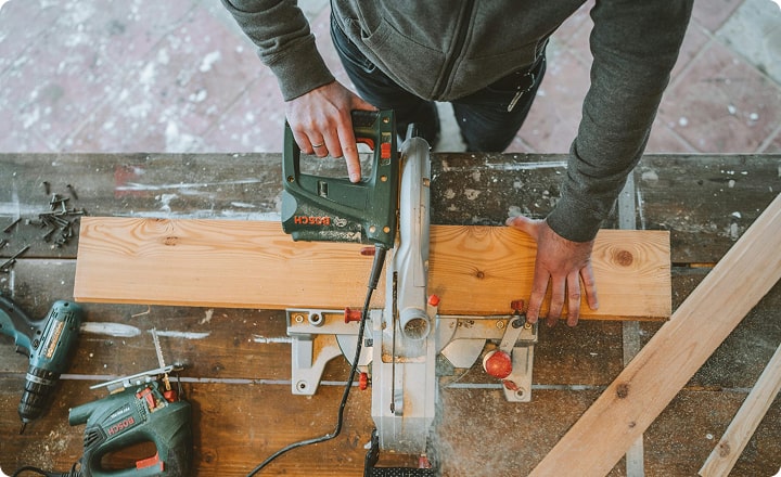 Un homme scie une planche de bois