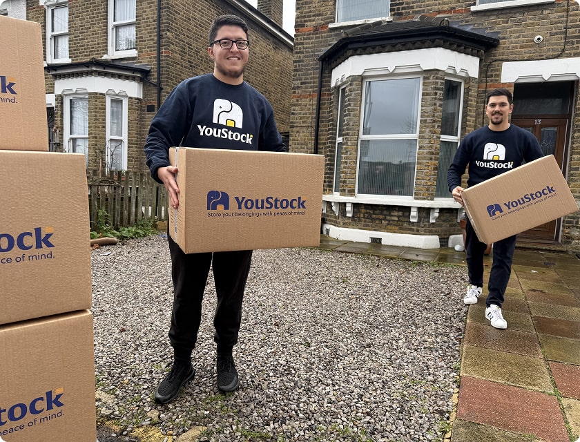 Two YouStock movers, each holding a moving box in their hands
