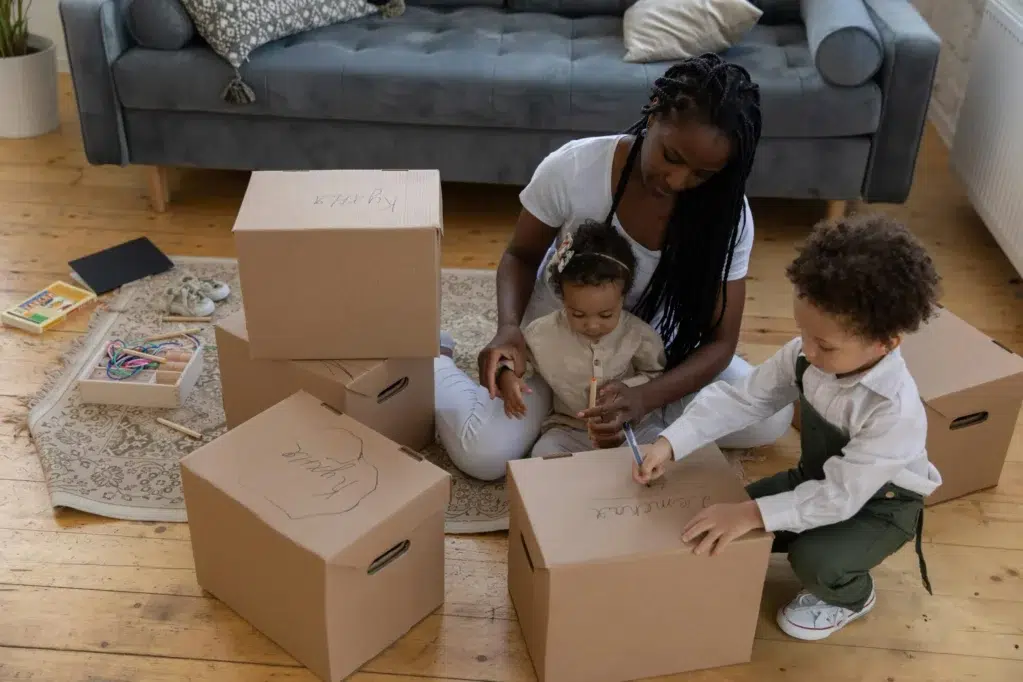 Une maman avec ses deux enfants en train de faire des cartons de déménagement