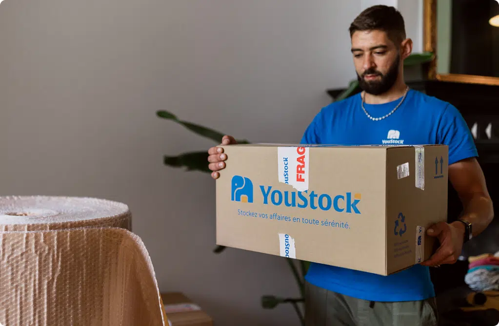 Un déménageur YouStock porte un carton de stockage