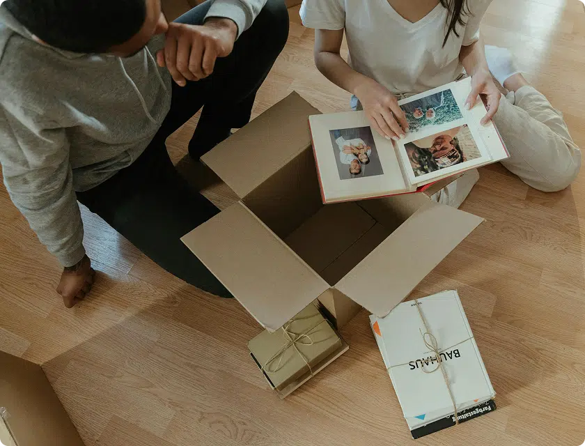 Couple mettant en carton de déménagement des albums photos de leur mariage