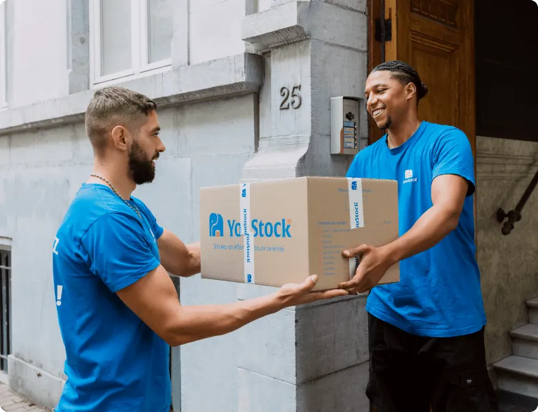 Deux déménageurs YouStock se transmettent un carton de stockage