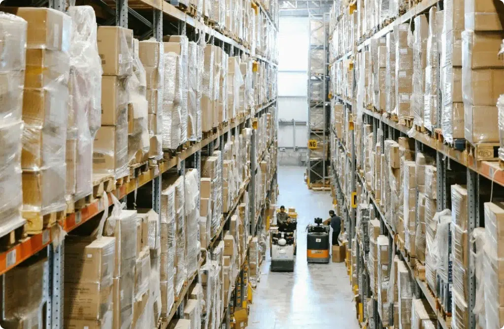 Une allée d'un entrepôt où des palettes de cartons sont empilées et stockées
