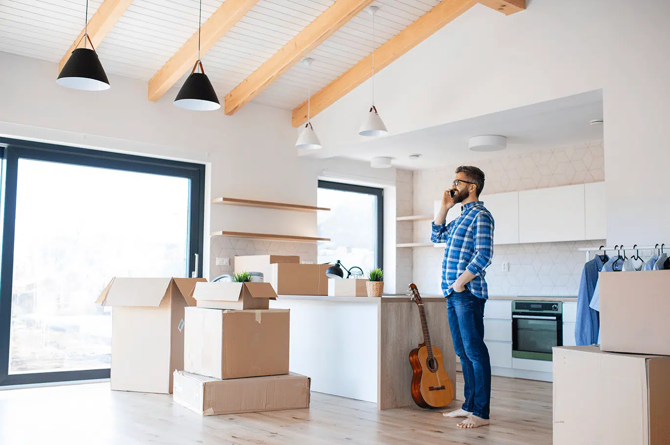 Un jeune homme au téléphone au milieu de cartons de déménagement