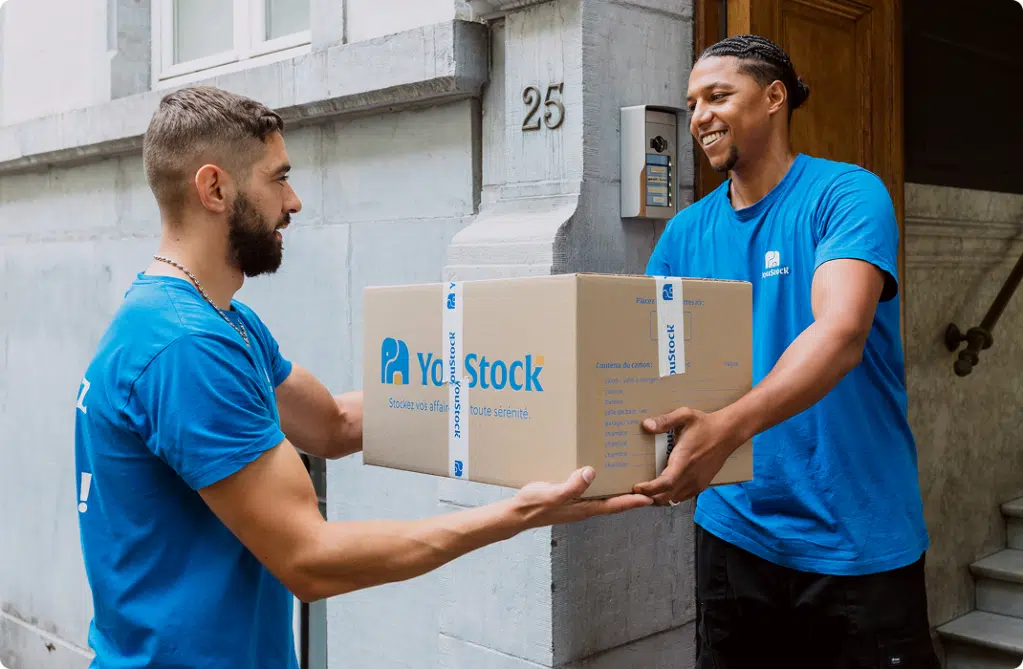 deux déménageurs YouStock se transmettent un carton de déménagement
