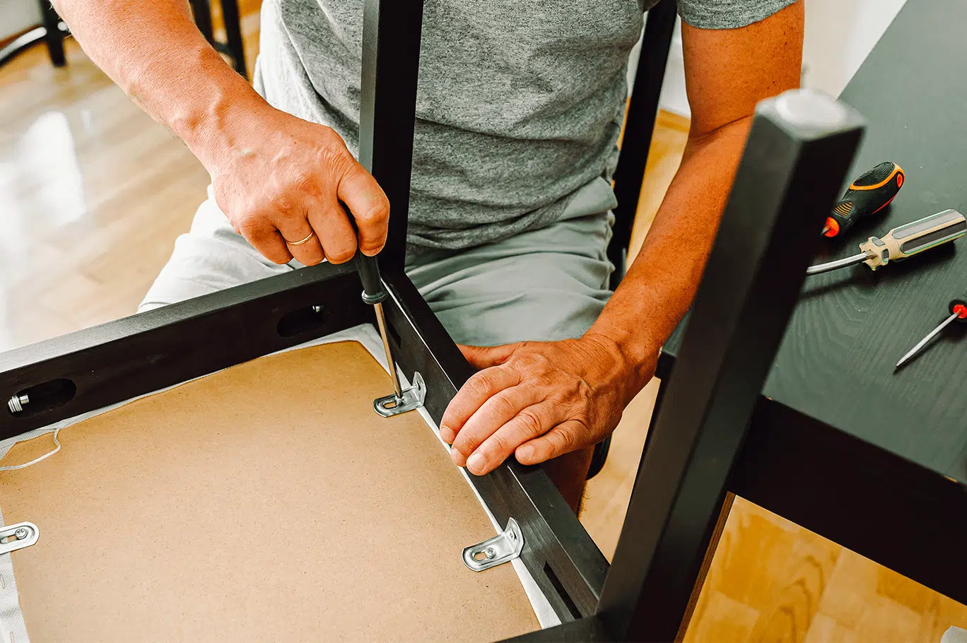 Un homme fixe une cheville sous une chaise