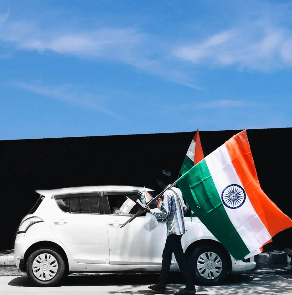 man by car holding flag of india