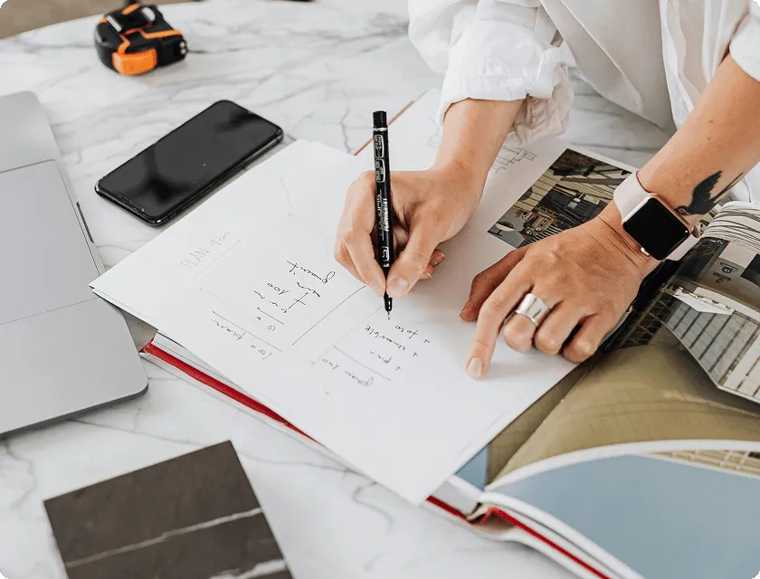 Zoom in on the hands of a woman writing on a piece of paper on an architect's desk.