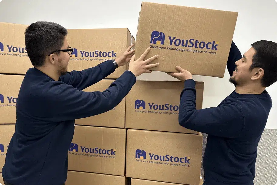 Two YouStock removal men stack storage boxes.