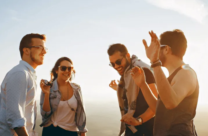 3 men and 1 woman standing happy in the sun