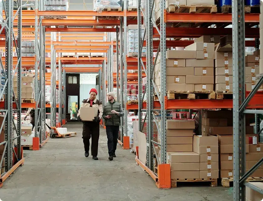 Two employees walking down the aisle of a storage warehouse
